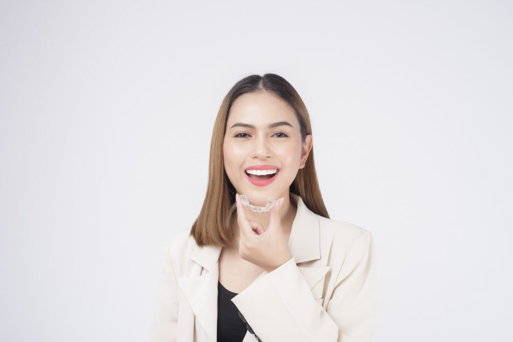 young smiling woman holding invisalign braces in studio, dental healthcare and orthodontic concept