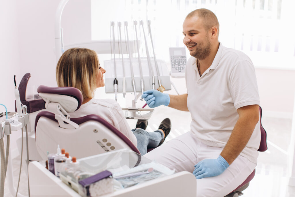 the dentist consults with his female patient sitting in a dental