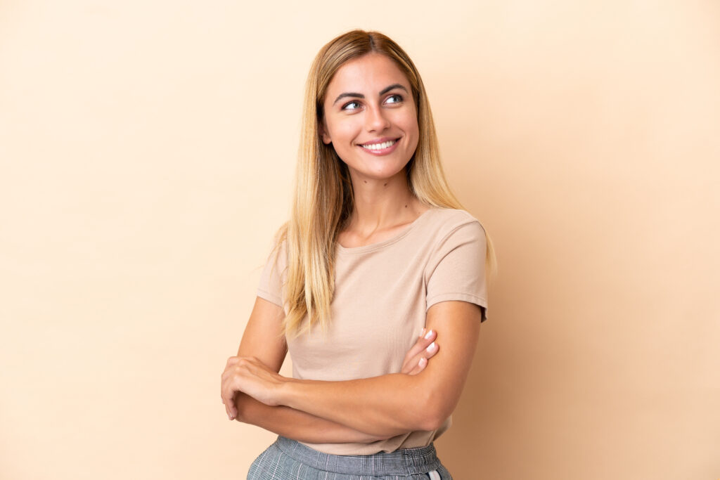 blonde uruguayan girl isolated on beige background happy and smiling