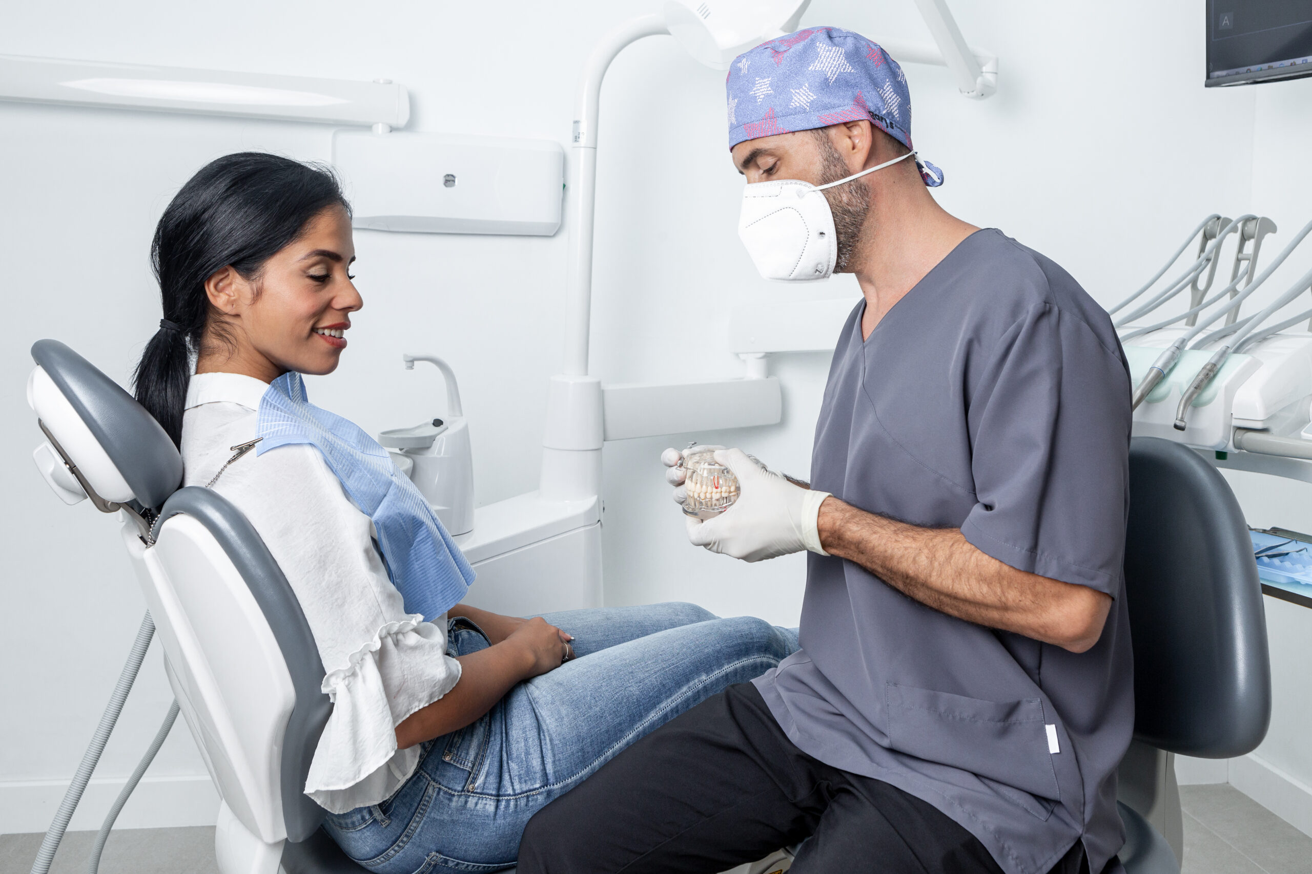 dentist showing a dental mould to a patient sitting in a dental clinic.